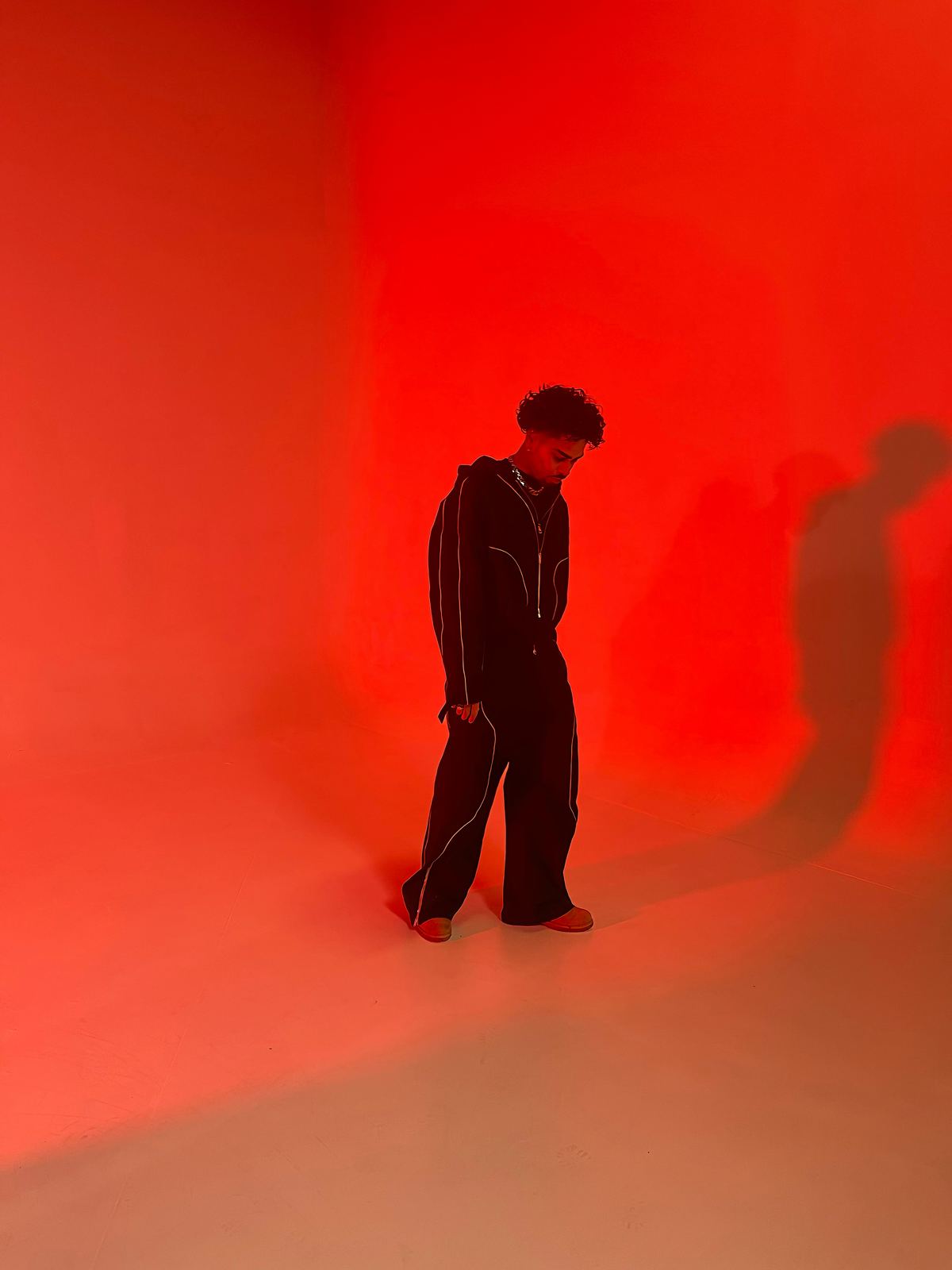 Donovan en studio, silhouette entière baignée dans une lumière rouge saturée.