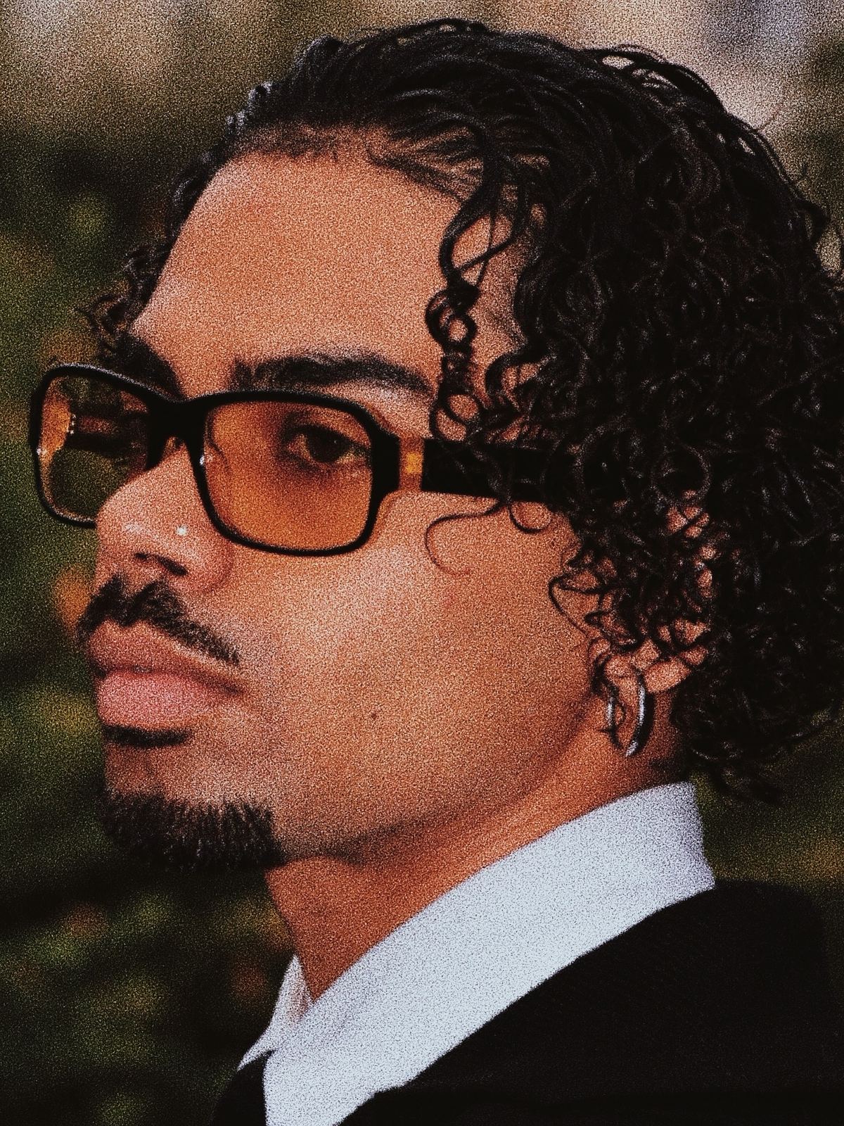 Portrait rapproché de Donovan en lunettes, veste noire et chemise blanche.