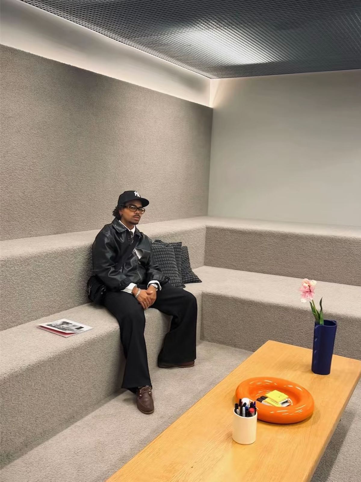 Donovan assis sur des gradins moquettés, dans un intérieur design.